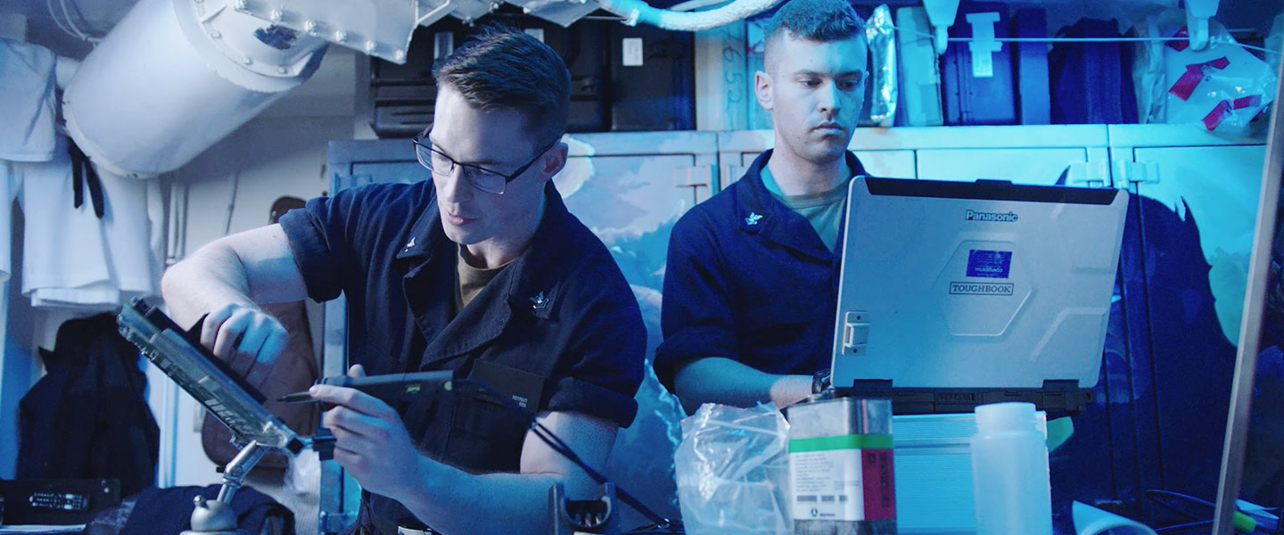 Two United States Navy Electronics Technicians Nuclear reinstall a capacitor bank aboard a submarine.