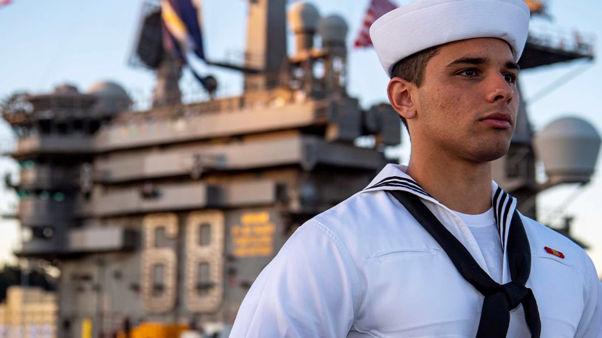 A Navy Sailor stands before a vessel.